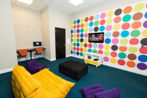 community room with playful decorations, brightly colored wallpaper, tv, computers, and lounge chairs