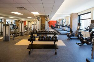 large fitness center with cardio equipment, weights, facing large windows