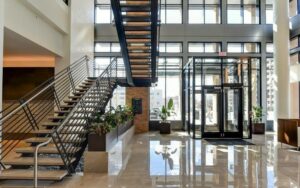 bright lobby with floor to ceiling windows, large staircase, facing front door