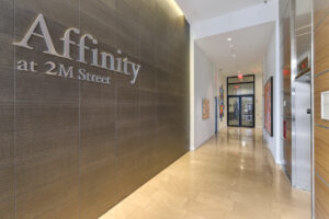 Interior lobby hallway, affinity at 2M Street Signage, tile floor, tile wall, elevator, contemporary art on the walls.