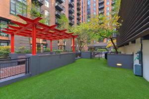 Outdoor dog park, planter boxes with trees, red pergola, benches and seats places throughout the square