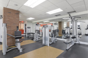 Interior Fitness Center, multiple weight lifting machines, mirrored wall, padded floor.